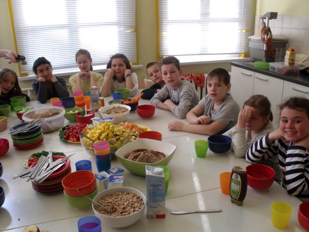 Schüler sitzen an einem gedeckten Tisch